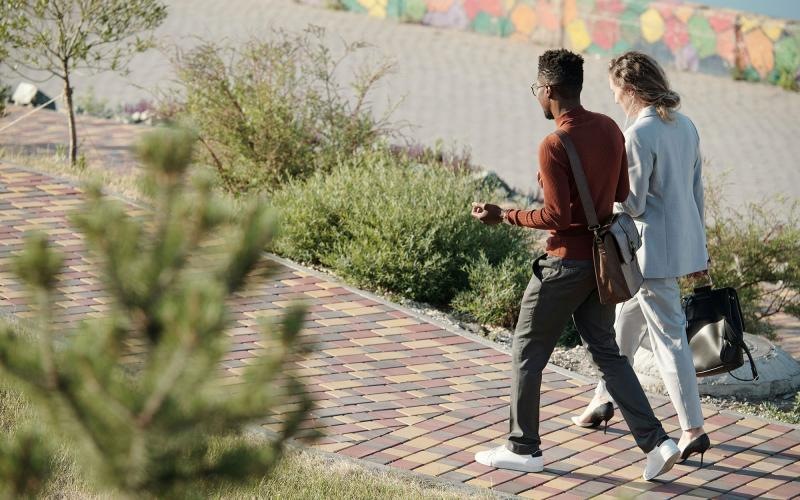 A man and woman walking on a brick sidewalk.