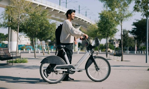A man walking with a city bike.